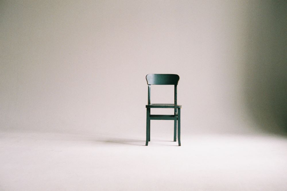 Green chair in front of white wall