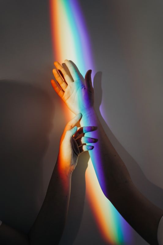 Persons hands with rainbow streams of light