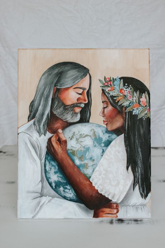 Man and woman of color wearing white clothing holding earth between them