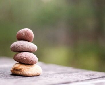 Four pebbles stacked on table outdoors