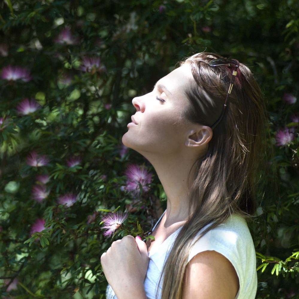 Woman with closed eyes and head tilted upwards towards the sunlight