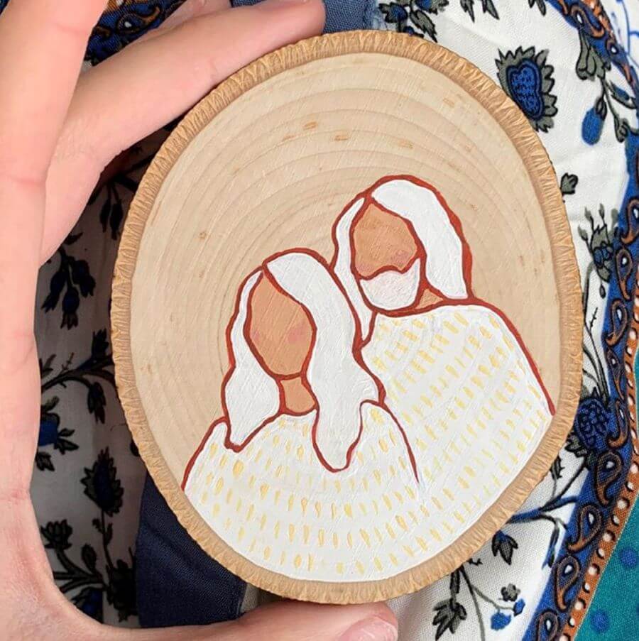 Two white figures painted on wooden disk