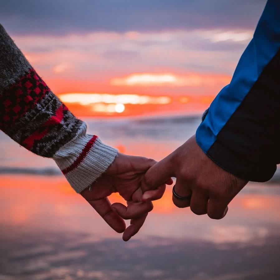 holding hands in front of a sunset