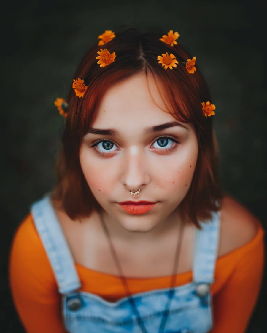Girl with orange flowers in her hair looking at camera