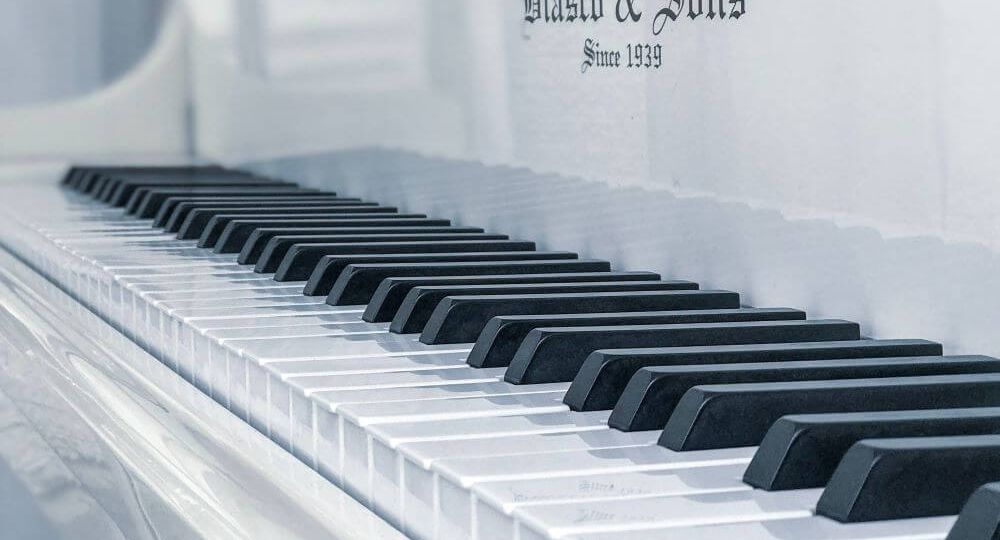 Angled photo of white piano with black and white keys