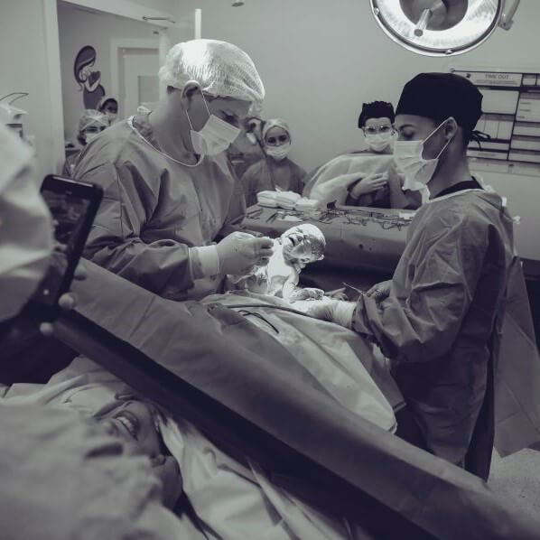 Black and white photo of doctors and nurses performing a c-section