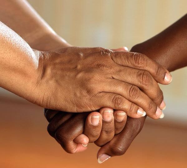 Two black hands reaching out and holding another black hand.
